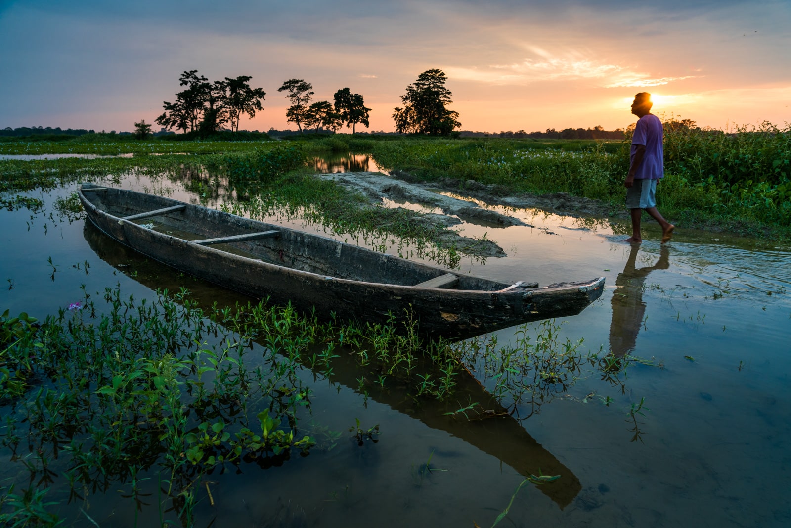 Man walking by a boat on Majuli Island, India