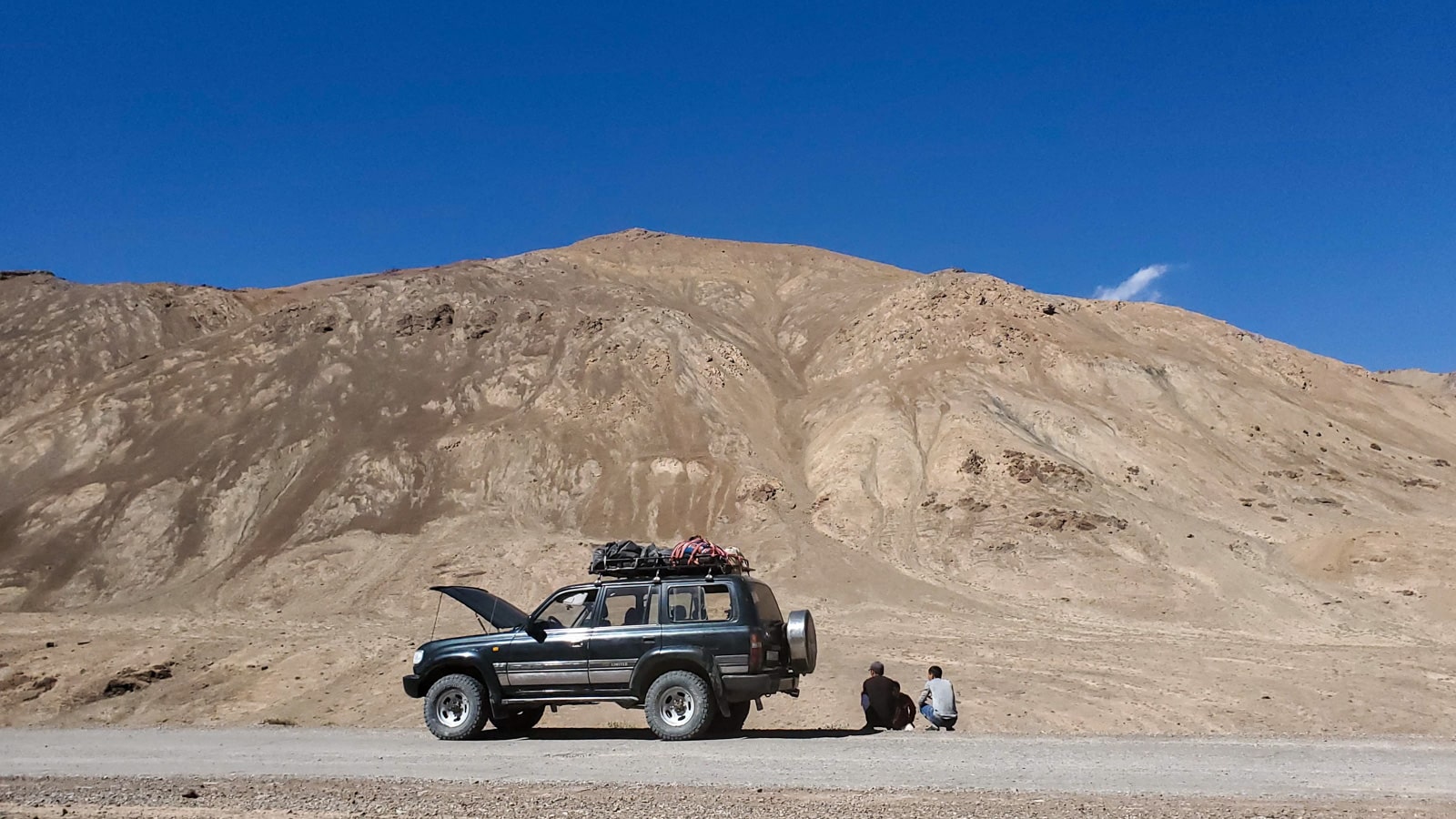 Men sitting by a jeep on the Pamir Highway in Tajikistan