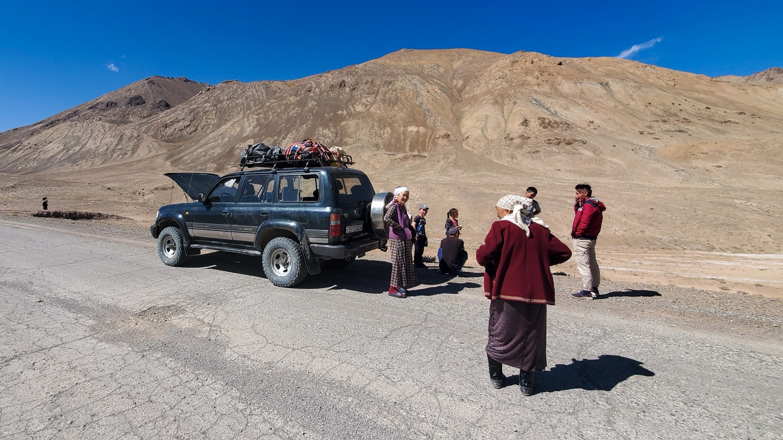 Kyrgyz passengers by a jeep on the Pamir Highway in Tajikistan