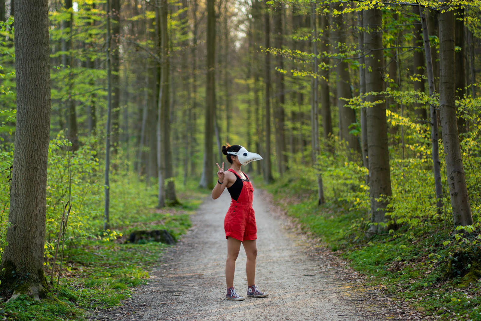 Me in a plague doctor mask making a peace sign in a spring forest in Tervuren, Belgium