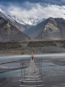 Woman walking on the Passu suspension bridge in Hunza, Pakistan