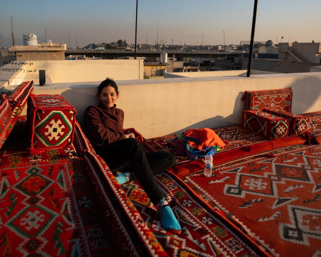 Solo female traveler relaxing on a rooftop of carpets in Mosul, Iraq