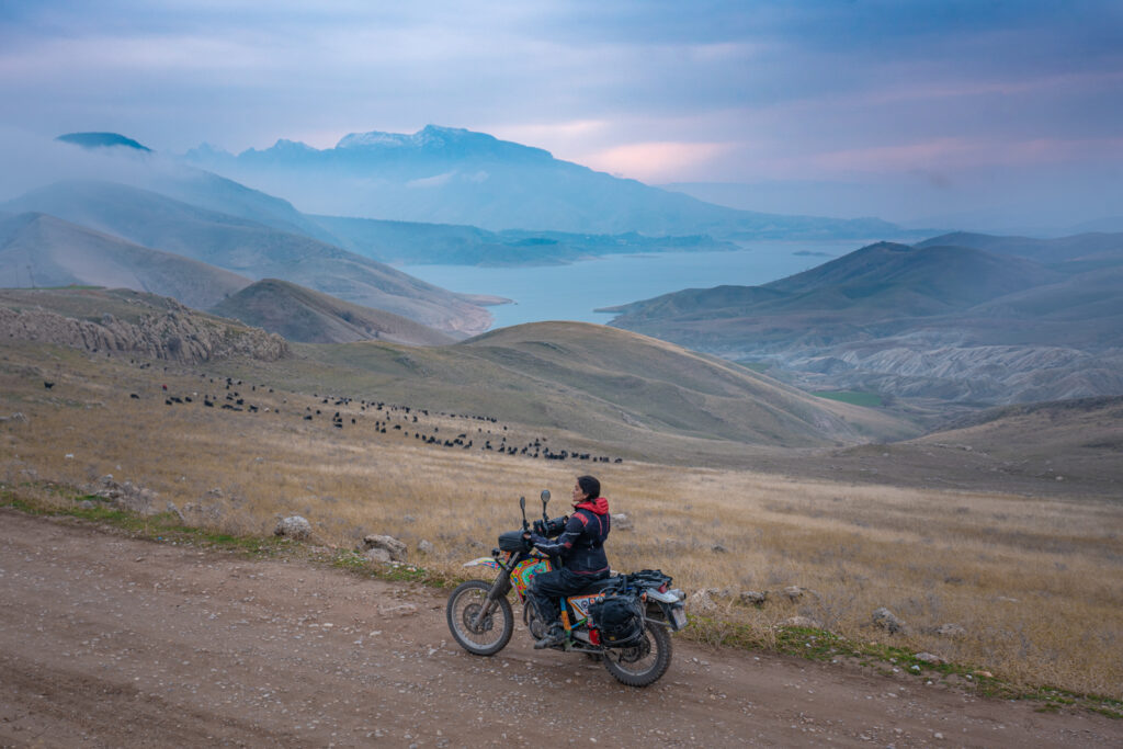 Alex on her motorcycle on an offroad track in front of Lake Dukan in Kurdistan
