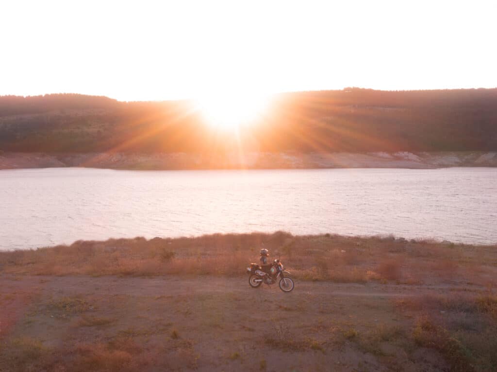 Leaving your foreign vehicle in Turkey - Drone shot of a motorcycle and sunset over Sevisler Lake in Turkey